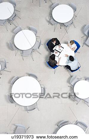 Stock Image - Overhead view of informal business meeting at table of staff canteen. Fotosearch