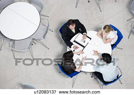 Stock Photo - Overhead view of informal business meeting at table of staff canteen. Fotosearch
