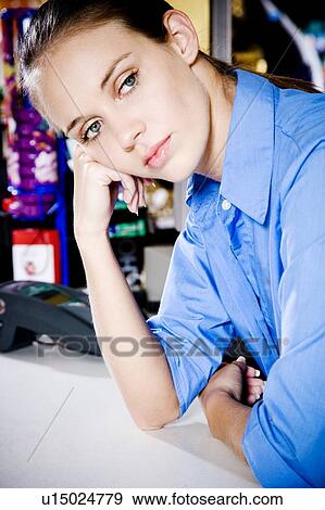 Stock Photo - Portrait of a bored supermarket checkout assistant. Fotosearch