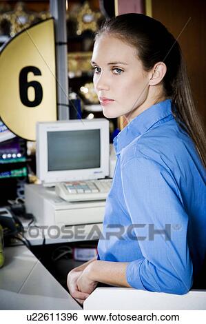 Stock Photograph - Portrait of a bored supermarket checkout assistant. Fotosearch