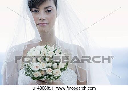 Stock Image - Portrait of a bride holding her bouquet. Fotosearch