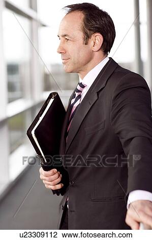 Stock Image - Portrait of a businessman holding a leather case with briefing papers. Fotosearch
