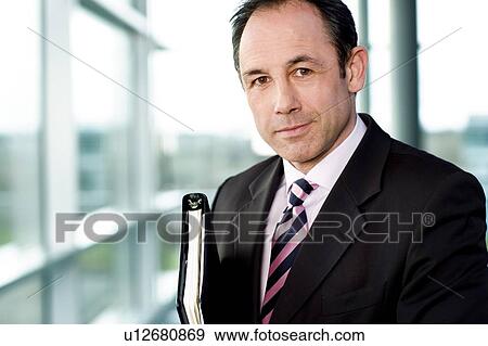 Stock Photo - Portrait of a businessman holding a leather case with briefing papers. Fotosearch