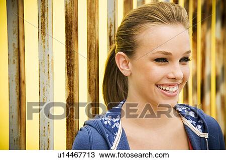 Stock Image - Portrait of a girl leaning against railing bars. Fotosearch