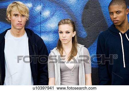 Stock Image - Portrait of a group of young friends hanging out in front of a graffiti covered wall . Fotosearch