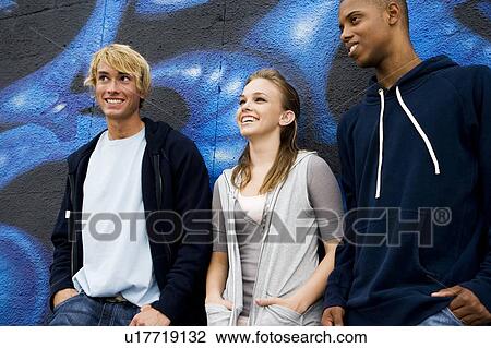 Stock Image - Portrait of a group of young friends hanging out in front of a graffiti covered wall . Fotosearch