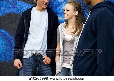 Stock Photo - Portrait of a group of young friends hanging out in front of a graffiti covered wall . Fotosearch