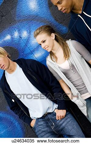Stock Photography - Portrait of a group of young friends hanging out in front of a graffiti covered wall . Fotosearch