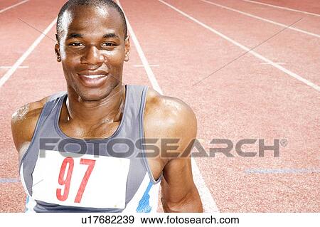 Stock Photo - Portrait of a male athlete resting sitting on a running track. Fotosearch