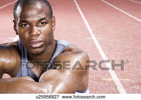 Portrait of a male athlete resting sitting on a running track View Large Photo Image Stock Photo - Portrait of a male athlete resting sitting on a running track. Fotosearch