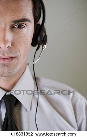 Stock Image - Portrait of a man using a call centre headset. Fotosearch