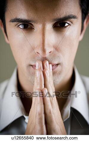 Stock Image - Portrait of a man with his hands in a praying position . Fotosearch