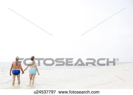Portrait of a senior couple hand in hand walking in the sea View Large Photo Image Stock Photo - Portrait of a senior couple hand in hand walking in the sea. Fotosearch