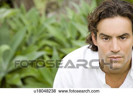 Stock Photo - Portrait of a serious looking man in a tropical garden. . Fotosearch