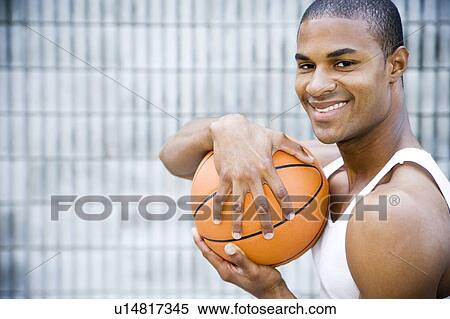 Stock Photography - Portrait of a smiling young African American man holding a basketball. . Fotosearch