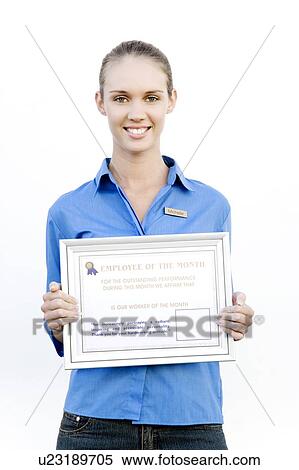 Stock Photography - Portrait of a supermarket assistant with an Employee of the Month certificate. Fotosearch