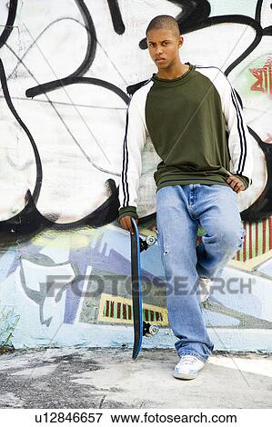 Portrait of a young African American man in front of a graffiti covered wall View Large Photo Image Stock Photo - Portrait of a young African American man in front of a graffiti covered wall. Fotosearch