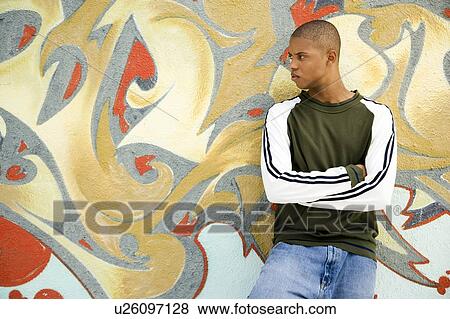 Portrait of a young African American man in front of a graffiti covered wall View Large Photo Image Stock Photo - Portrait of a young African American man in front of a graffiti covered wall. Fotosearch