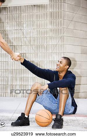 Portrait of a young African American man sitting greeting his friend View Large Photo Image Stock Photo - Portrait of a young African American man sitting greeting his friend. Fotosearch