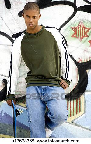 Portrait of a young African American man in front of a graffiti covered wall View Large Photo Image Stock Photography - Portrait of a young African American man in front of a graffiti covered wall. Fotosearch