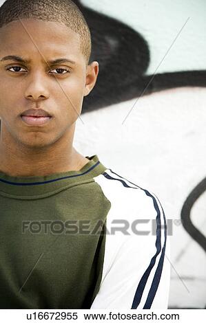 Stock Photography - Portrait of a young African American man in front of a graffiti covered wall. Fotosearch