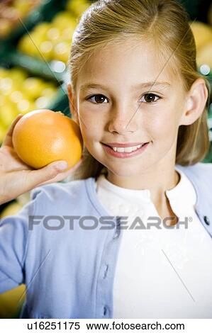Portrait of a young girl holding a grapefruit in a supermarket View Large Photo Image Stock Photography - Portrait of a young girl holding a grapefruit in a supermarket. Fotosearch