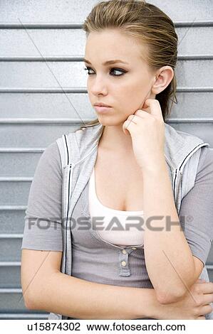 Stock Image - Portrait of a young girl leaning against a metallic wall . Fotosearch