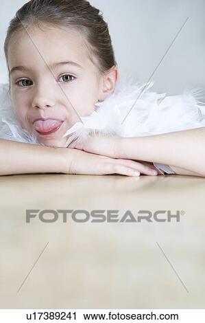 Stock Image - Portrait of a young girl with a feather boa in dressing up clothes poking her tongue out. Fotosearch