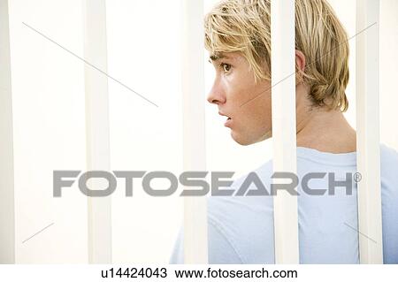 Portrait of a young man behind bars View Large Photo Image Stock Image - Portrait of a young man behind bars. Fotosearch