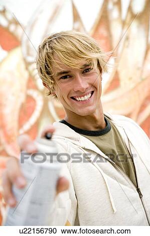 Portrait of a young man holding a spray can in front of a wall covered in graffiti View Large Photo Image Stock Image - Portrait of a young man holding a spray can in front of a wall covered in graffiti . Fotosearch