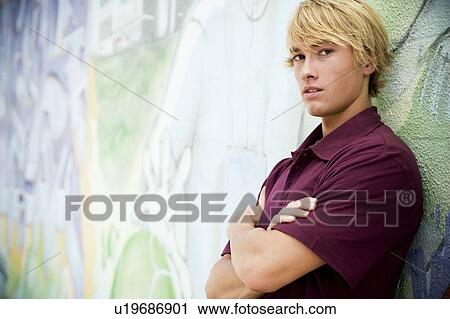 Portrait of a young man in front of a graffiti covered wall View Large Photo Image Stock Image - Portrait of a young man in front of a graffiti covered wall. Fotosearch