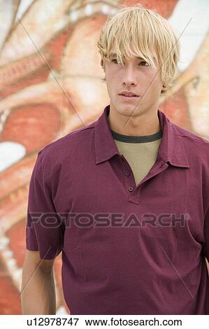 Stock Photo - Portrait of a young man in front of a graffiti covered wall. Fotosearch