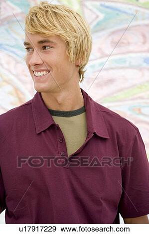 Stock Photo - Portrait of a young man in front of a graffiti covered wall. Fotosearch
