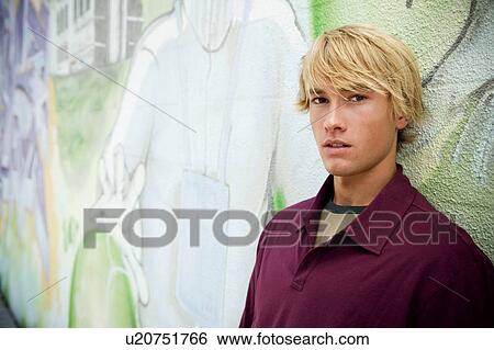 Portrait of a young man in front of a graffiti covered wall View Large Photo Image Stock Photograph - Portrait of a young man in front of a graffiti covered wall. Fotosearch