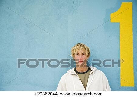 Portrait of a young man leaning against a green painted wall View Large Photo Image Picture - Portrait of a young man leaning against a green painted wall . Fotosearch