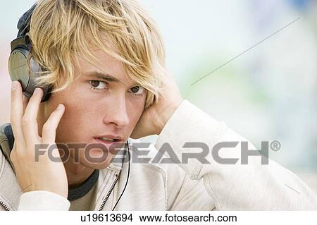 Picture - Portrait of a young man listening to music in front of a graffiti covered wall. Fotosearch