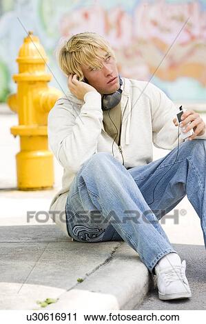 Portrait of a young man listening to music in front of a graffiti covered wall View Large Photo Image Stock Image - Portrait of a young man listening to music in front of a graffiti covered wall. Fotosearch