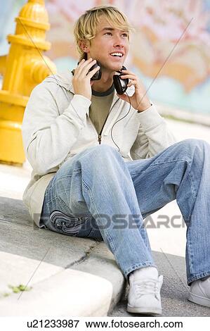 Stock Photo - Portrait of a young man listening to music in front of a graffiti covered wall. Fotosearch