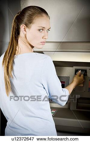 Stock Photo - Portrait of a young woman using an ATM cash machine. Fotosearch