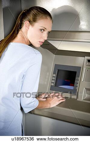 Portrait of a young woman using an ATM cash machine View Large Photo Image Stock Photograph - Portrait of a young woman using an ATM cash machine. Fotosearch