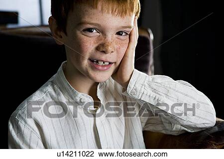 Stock Image - portrait of ginger haired boy leaning face on hand. Fotosearch