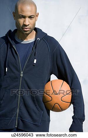 Stock Image - Portrait of young African American man holding a basketball. Fotosearch
