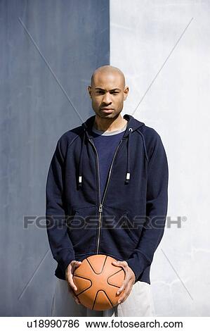 Stock Photograph - Portrait of young African American man holding a basketball. Fotosearch
