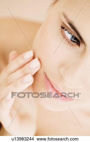 Picture - Portrait of young woman touching her cheek. Fotosearch