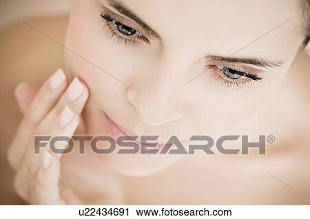 Portrait of young woman touching her cheek View Large Photo Image Stock Image - Portrait of young woman touching her cheek. Fotosearch