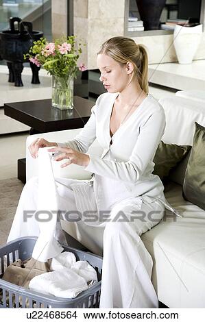Picture - Pregnant woman folding the washing at home. Fotosearch