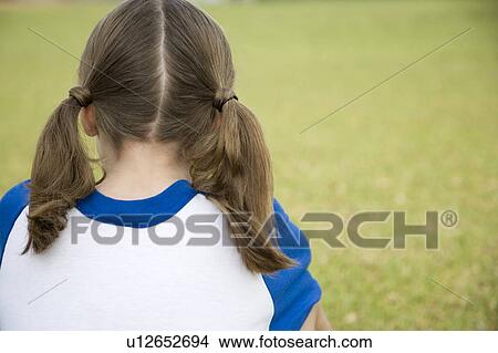 Picture - Rear view girl sitting on the grass. Fotosearch