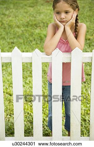 Stock Image - sad little girl leaning on fence . Fotosearch