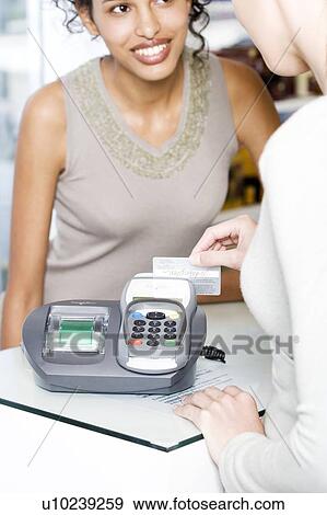 Stock Photo - Sales assistant swiping credit card. Fotosearch