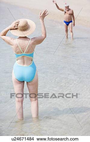 Senior couple waving to each other at the beach View Large Photo Image Picture - Senior couple waving to each other at the beach . Fotosearch